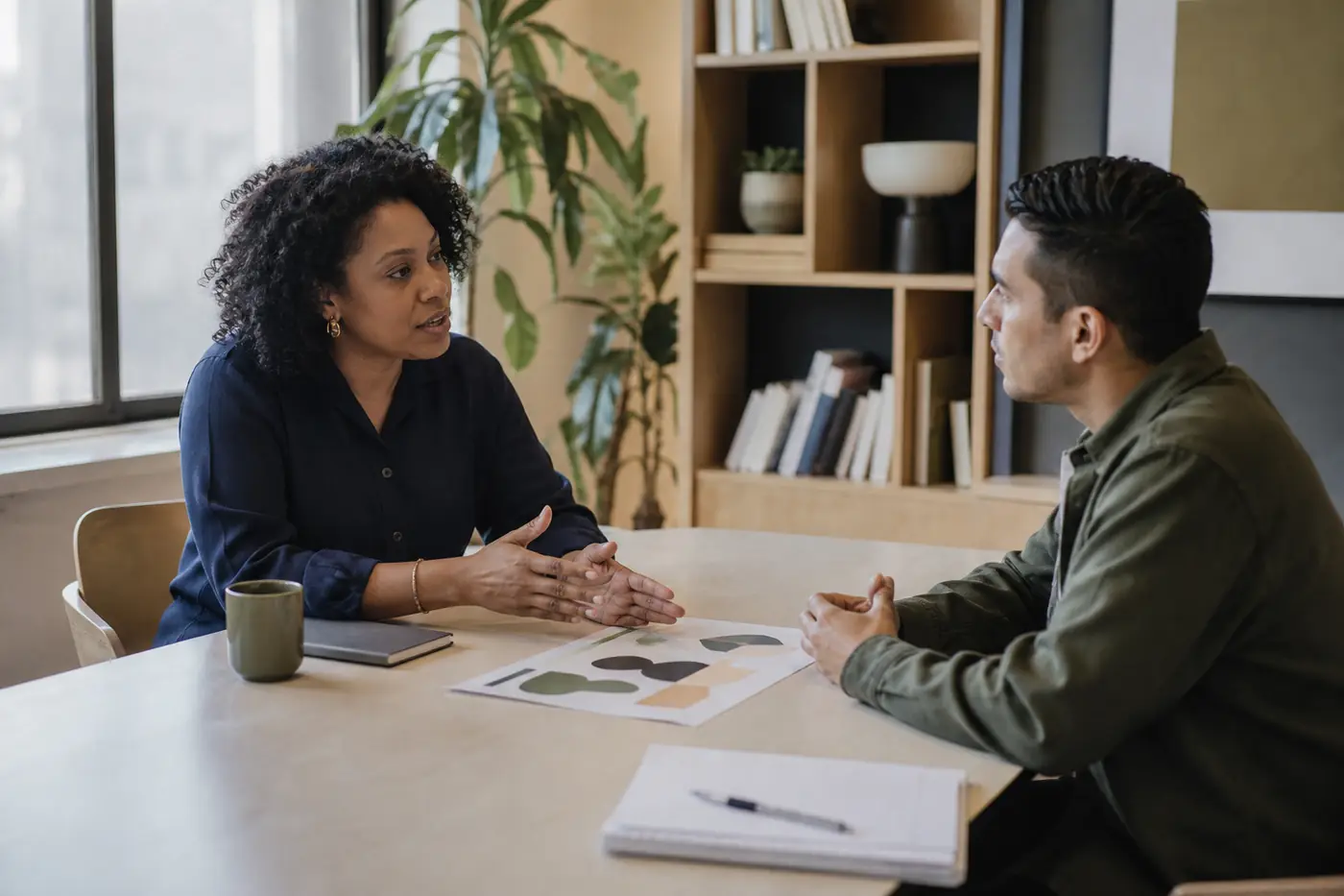 A hiring manager and candidate discussing a work sample in a bright office