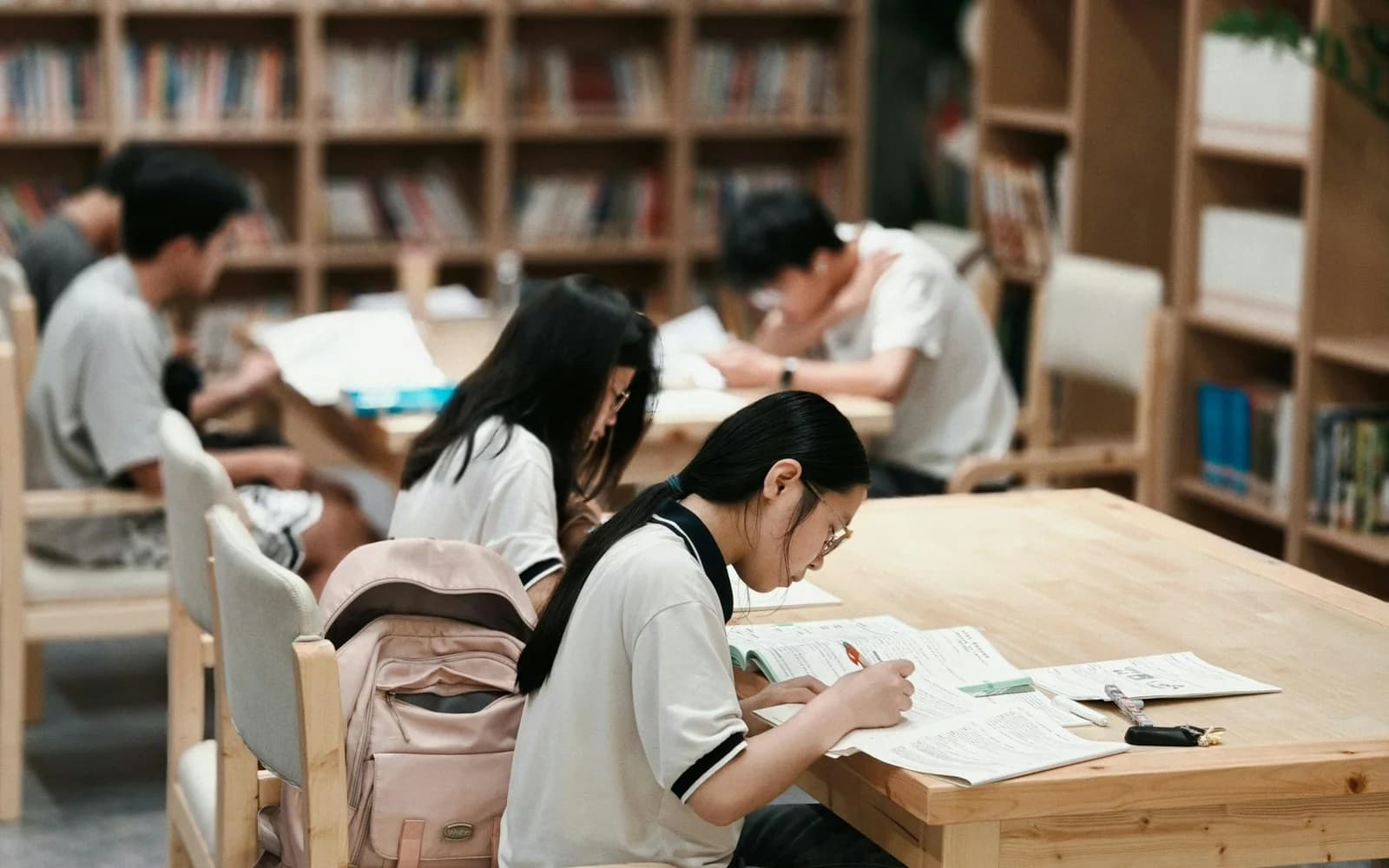 Students read and write together at a library table.