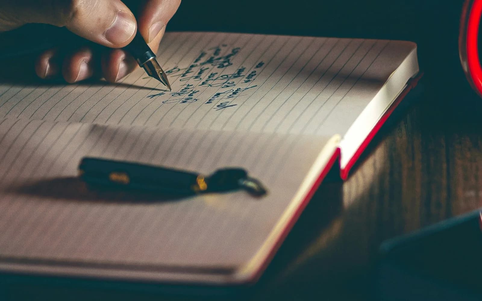 A hand writes a paper journal entry with a fountain pen.