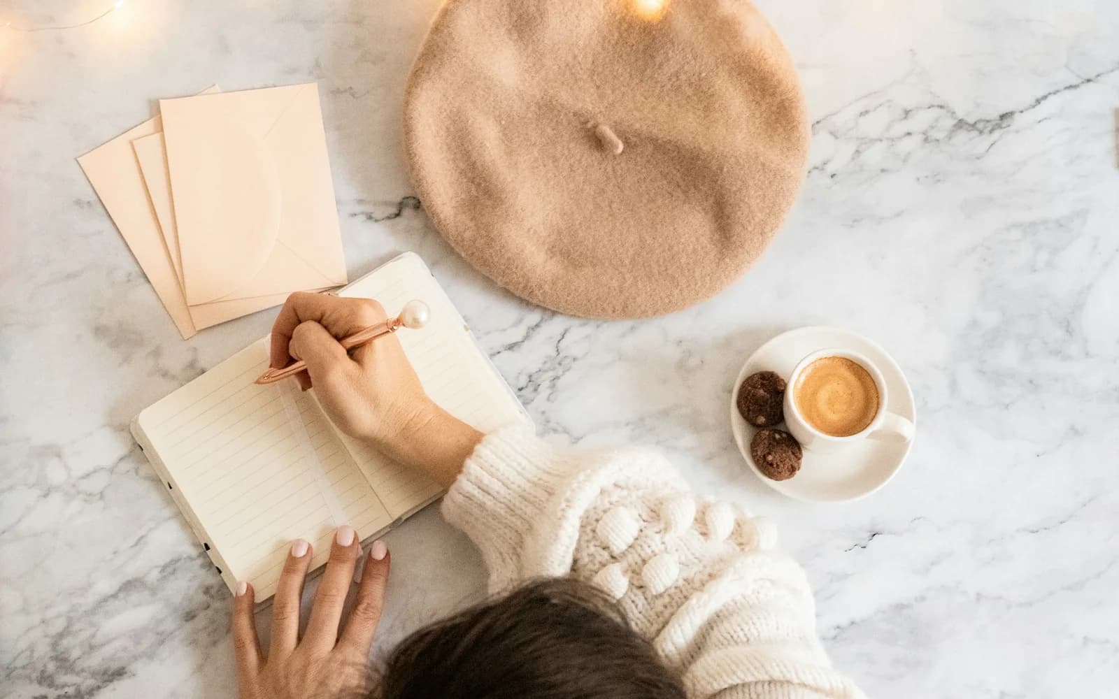 A person writes a brief notebook entry beside a cup of coffee.
