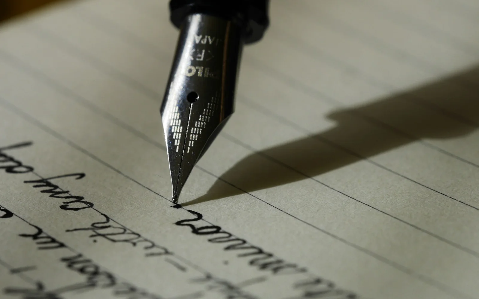 A fountain pen moves across a lined journal page.
