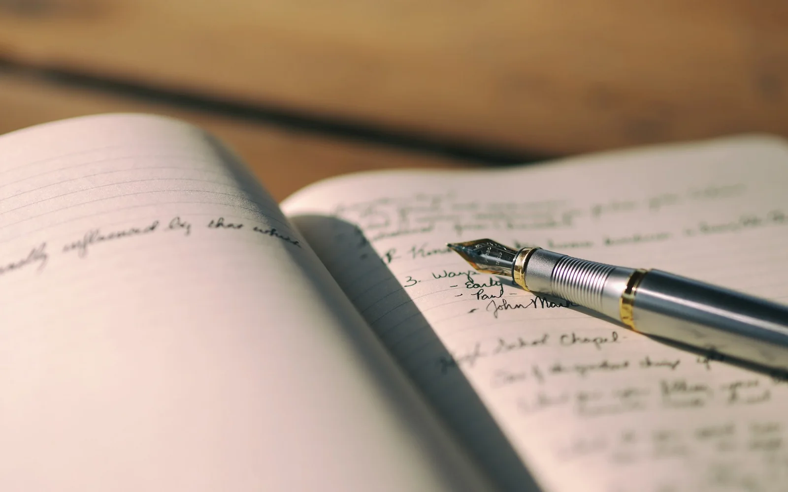 A fountain pen rests across handwritten journal pages.