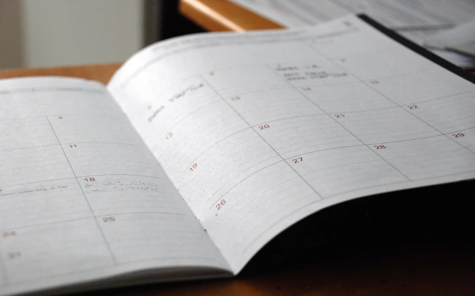 An open monthly planner rests on a wooden table.