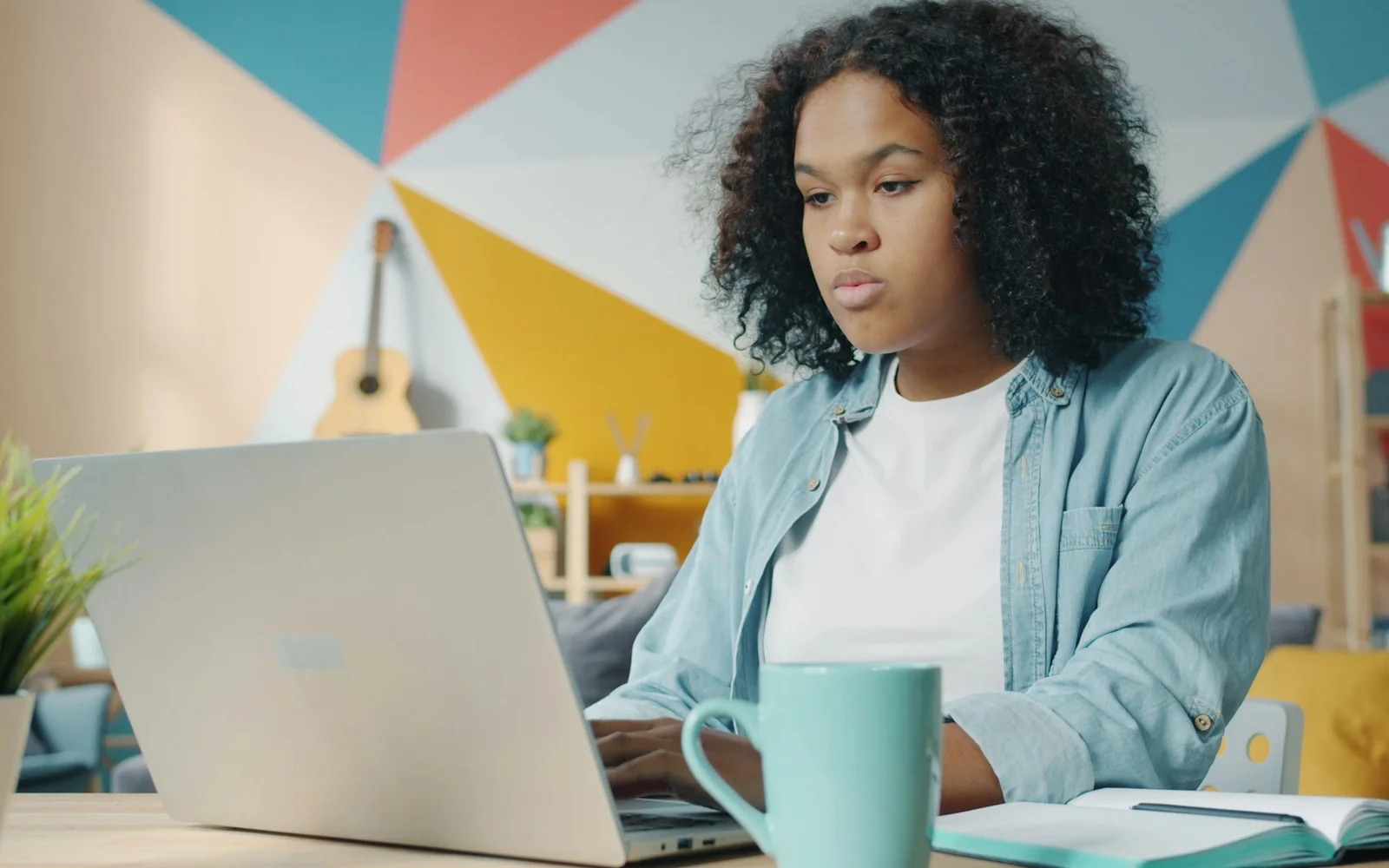 A woman works on a laptop from a table at home.