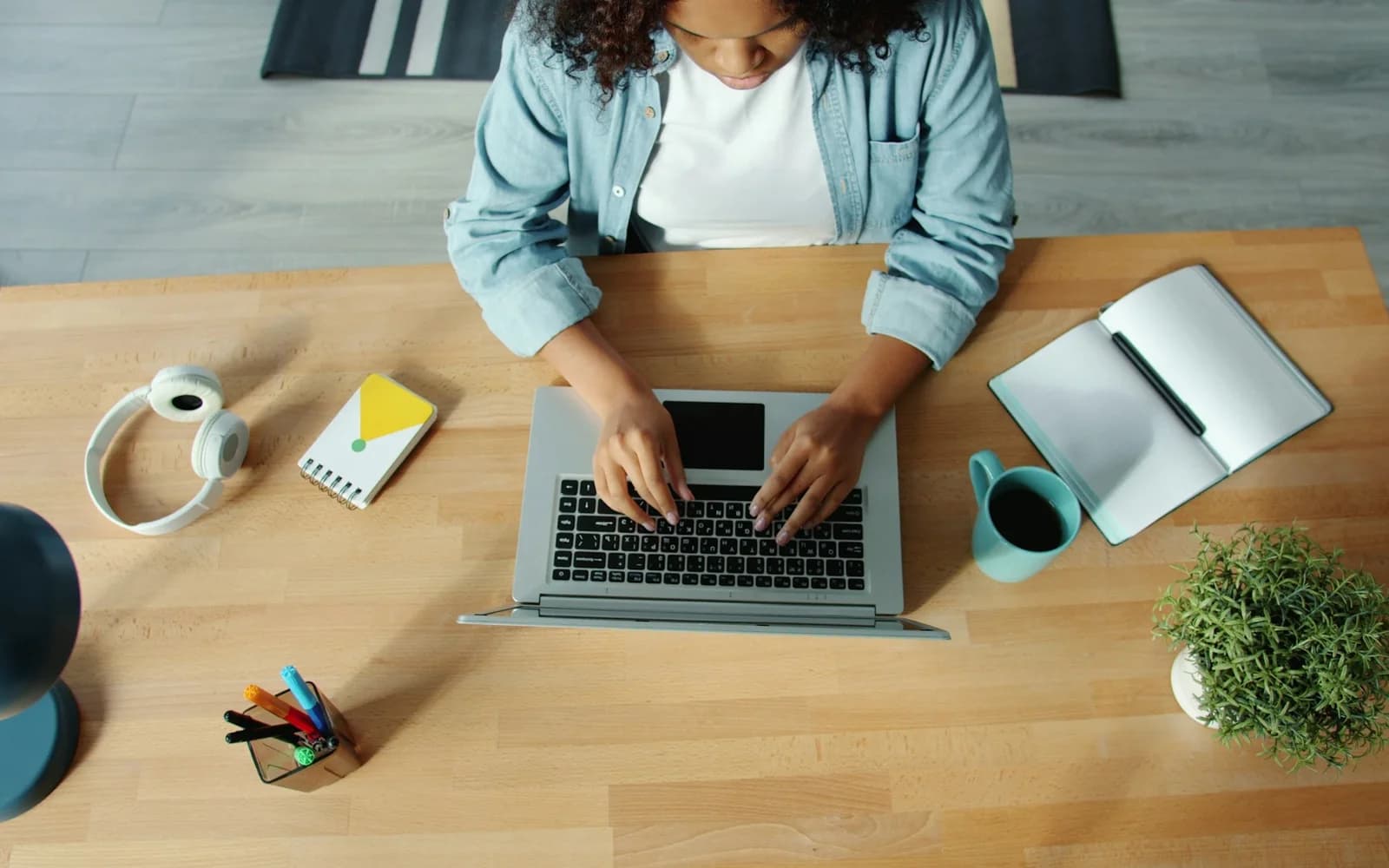 A woman types on a laptop at a shared wooden table.